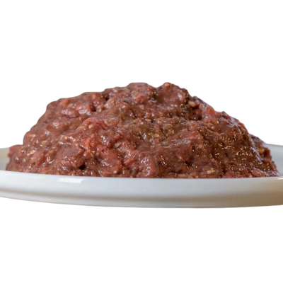 Barfgold Rinderinnereienmix, gewolft, 500g, auf einem weißen Teller. Die Mischung hat eine grobe, fleischige Textur in dunklem Rot.