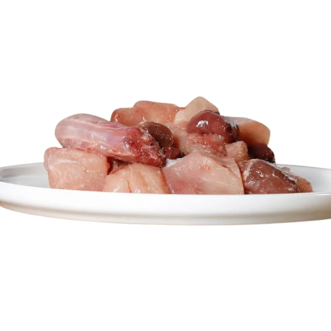 Rohes Hühnerfleisch auf einem weißen Teller, bestehend aus verschiedenen Fleischstücken, darunter Hühnerleber und Hühnerherzen.