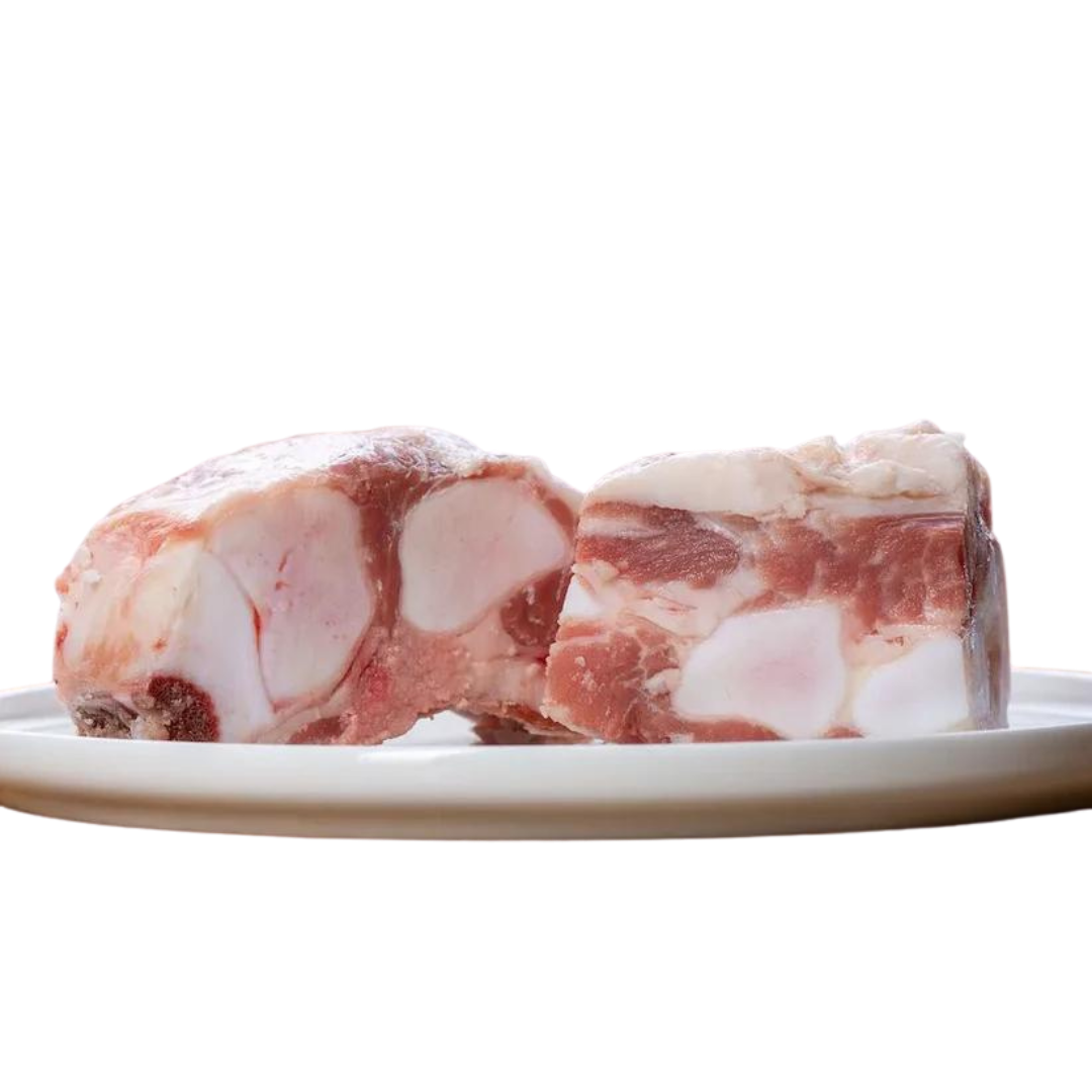 Zwei Stücke Kalbsbrustbein auf einem Teller. Das Fleisch hat eine marmorierte Struktur mit sichtbaren Knochen. Marke: Barfgold, Inhalt 1kg