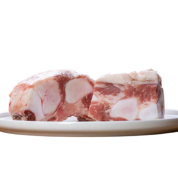 Zwei Stücke Kalbsbrustbein auf einem Teller. Das Fleisch hat eine marmorierte Struktur mit sichtbaren Knochen. Marke: Barfgold, Inhalt 1kg