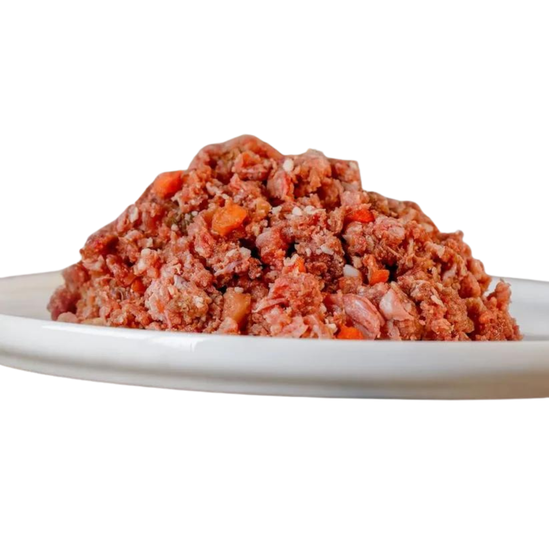 Barfgold Komplett Menü Lamm, 1 kg, auf einem weißen Teller. Das Futter ist grob gewolft und enthält sichtbare Stücke von Fleisch und Gemüse.