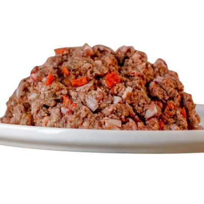 Barfgold Komplett Menü Rind, 1 kg, auf einem weißen Teller. Das Futter ist gewolft und enthält kleine Stücke von rotem Gemüse.