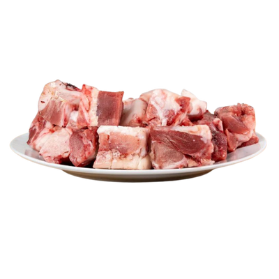 Ein Teller mit Stückchen von Lammfleisch, einige mit Fett, in verschiedenen Formen und Größen. Produkt von Barfgold, 1 kg.