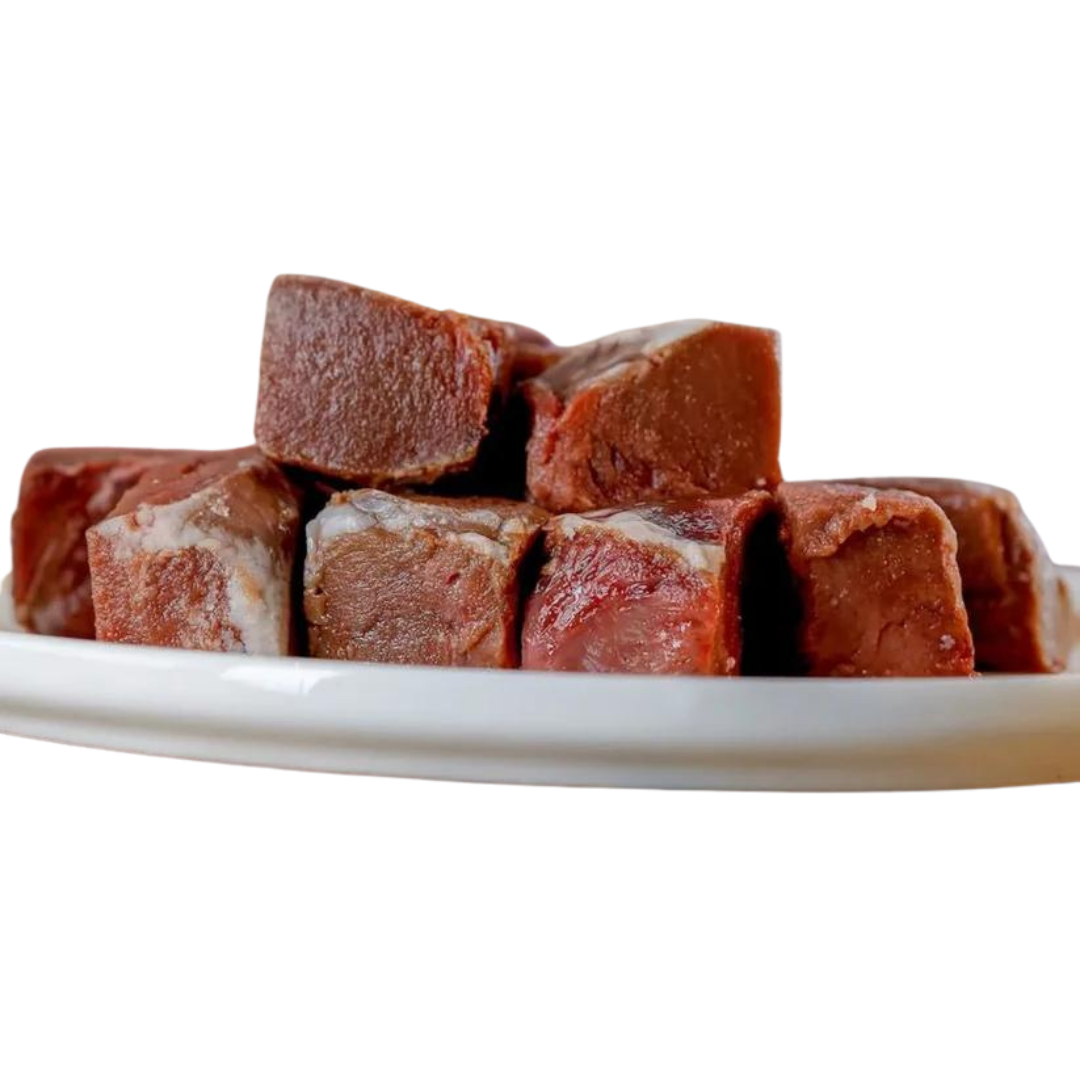 Sechs gefrorene, quadratische Stücke von Lammherz auf einem weißen Teller. Marke 'Barfgold'.