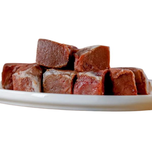 Sechs gefrorene, quadratische Stücke von Lammherz auf einem weißen Teller. Marke 'Barfgold'.