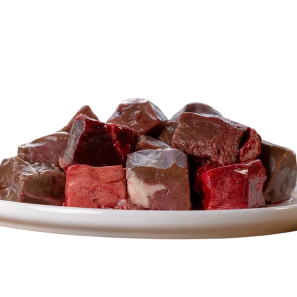 Stapel von gefrorenen Fleischwürfeln in verschiedenen Rottönen auf einem weißen Teller. Produkt: 'Barfgold TK Lamminnereienmix 1kg'.