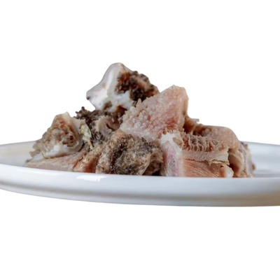 Stücke von Lamm-Pansen auf einem weißen Teller. Die Fleischstücke sind unregelmäßig geformt und zeigen eine Mischung aus hellen und dunklen Bereichen.