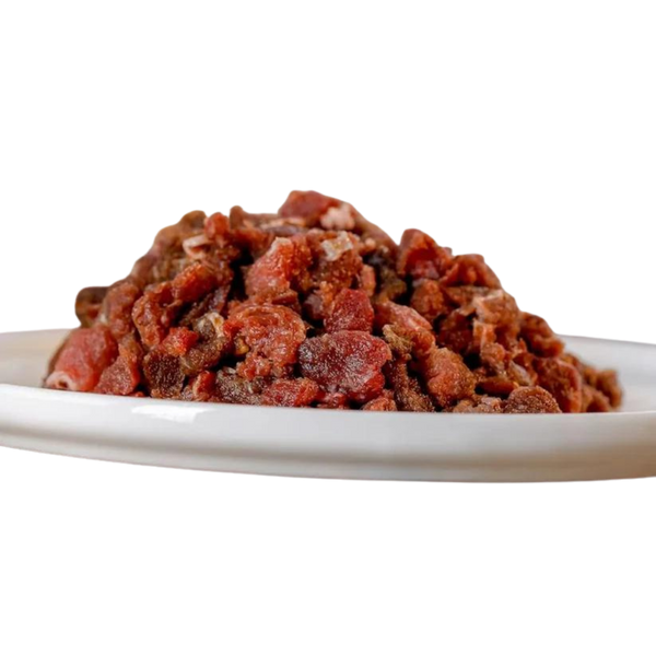 Rohes, gewolftes Pferdefleisch auf einem weißen Teller. Die Fleischstücke sind klein und unregelmäßig geformt.