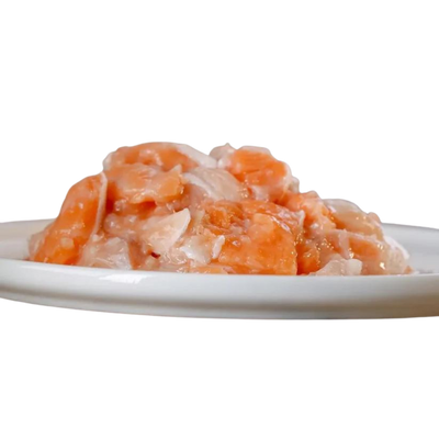 Weißer Teller mit Lachs und Fett. Stücke sind in verschiedenen Formen und Größen. Marke Barfgold