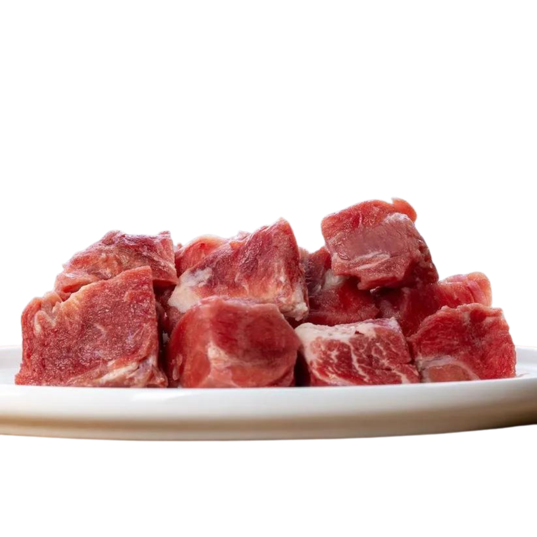 Weißer Teller mit Fleischstücken von der Ziege. Geformt in Würfel, einige mit und ohne Fett. Marke Barfgold