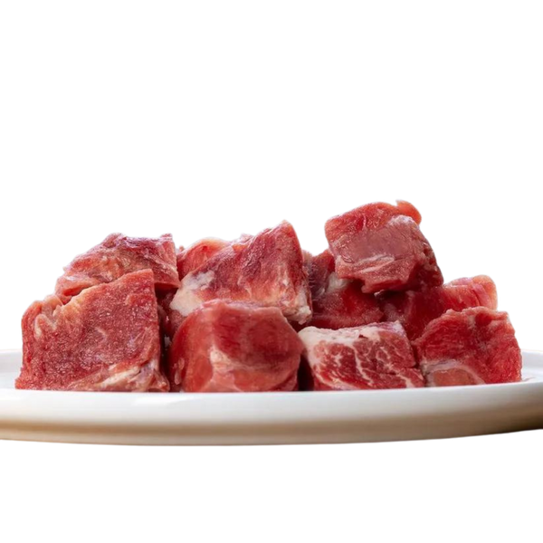 Weißer Teller mit Fleischstücken von der Ziege. Geformt in Würfel, einige mit und ohne Fett. Marke Barfgold
