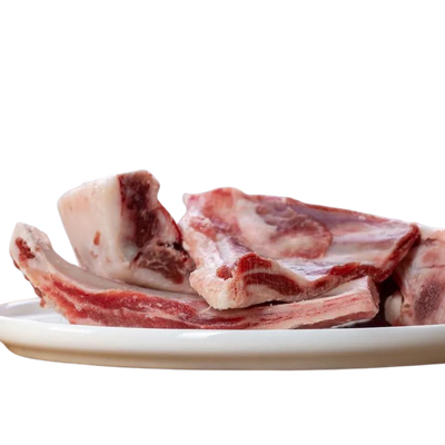 Weißer Teller mit Ziegenrippen. Man sieht die Knochen und das Fleisch. Marke Barfgold