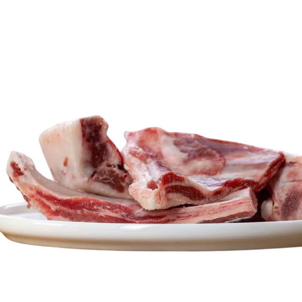 Weißer Teller mit Ziegenrippen. Man sieht die Knochen und das Fleisch. Marke Barfgold