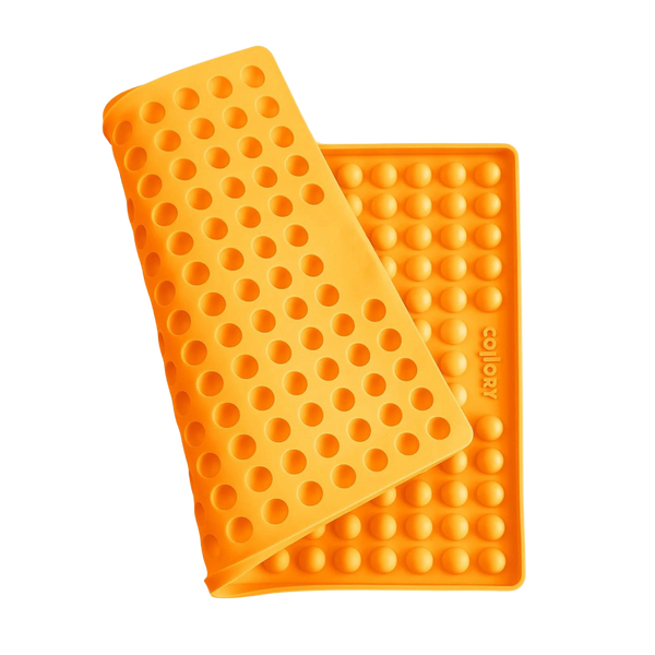 Orange Silikonmatte mit Noppen, die eine abgerundete Form hat. Die Matte hat eine wellenförmige Struktur.