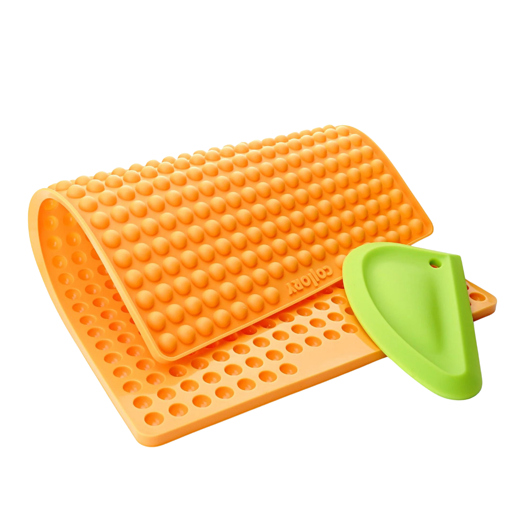 Orange Silikonmatte mit Noppen und einer grüne Kante, die eine abgerundete Form hat. Die Matte hat eine wellenförmige Struktur.