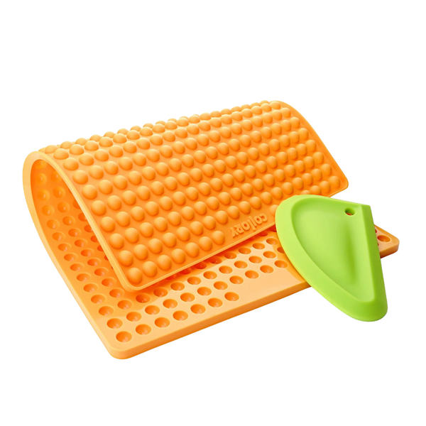 Orange Silikonmatte mit Noppen und einer grüne Kante, die eine abgerundete Form hat. Die Matte hat eine wellenförmige Struktur.