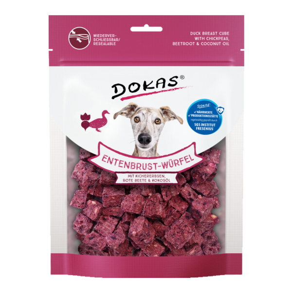 Verpackung von 'DOKAS Entenbrust-Würfel' mit einem Bild eines Hundes, der direkt in die Kamera schaut. Die Verpackung zeigt lila Würfel, die aus Entenbrust, Kichererbsen, roter Beete und Kokosöl bestehen.