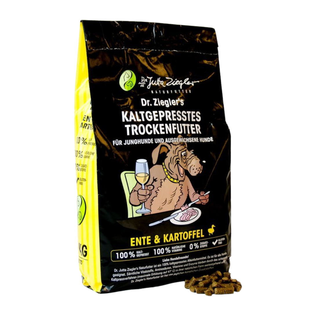 Schwarze Verpackung mit dem Text 'Dr. Ziegler's KALTGEPRRESSES TROCKENFUTTER FÜR JUNGHUNDE UND AUSGEWACHSENE HUNDE' und einem Hund, der ein Glas hält. Enthält Trockenfutter aus Ente und Kartoffeln.