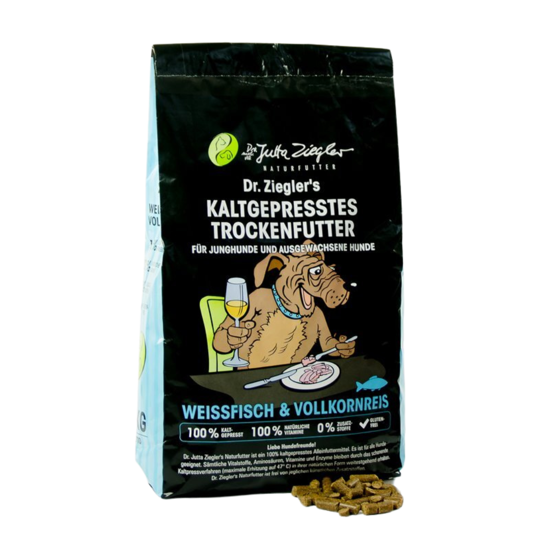 Schwarze Verpackung von Dr. Ziegler's kaltgepresstem Trockenfutter für Hunde mit Illustration eines Hundes, der an einem Tisch sitzt und Wein trinkt, Text 'Weissfisch & Vollkornreis' und Futterstückchen daneben.