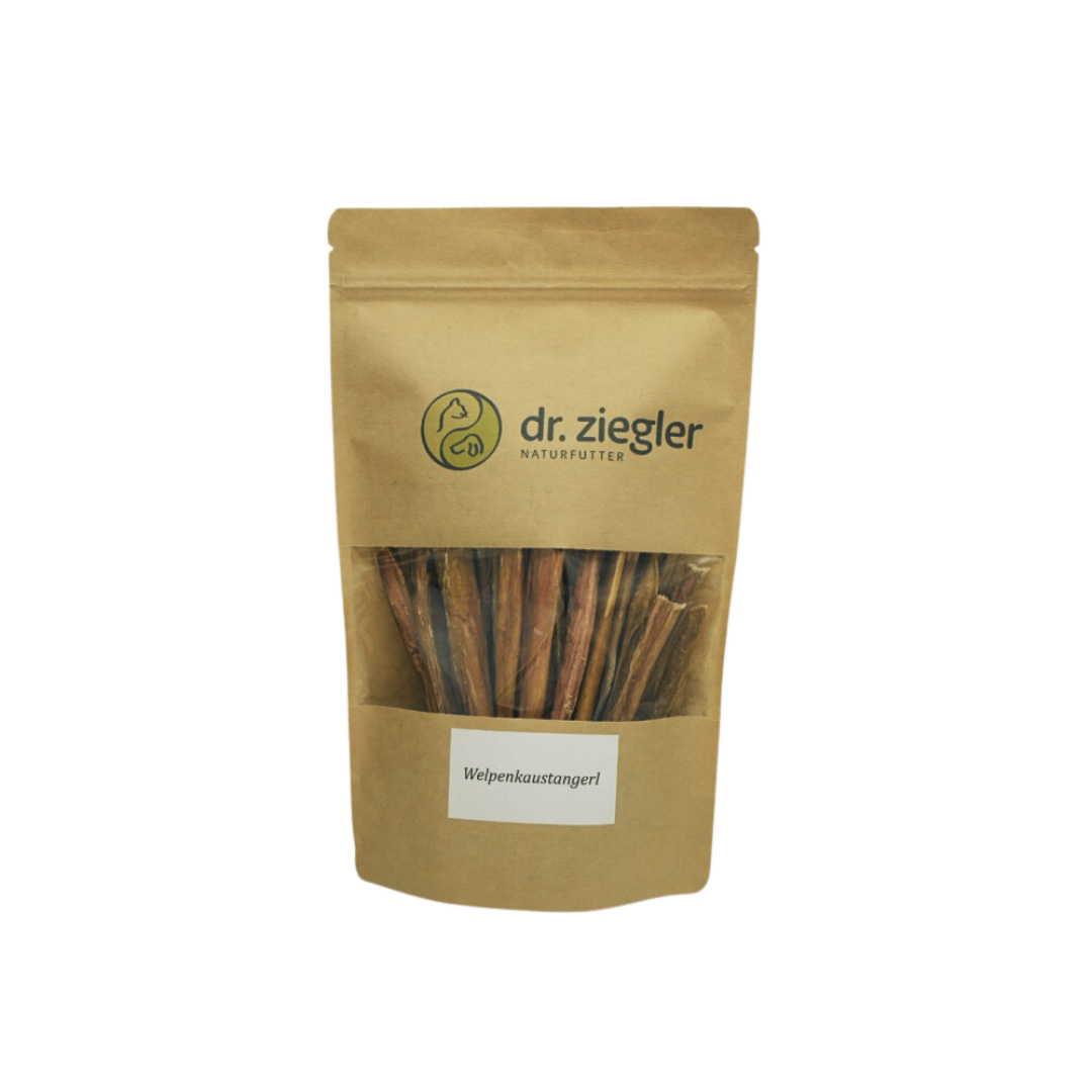 Braune Verpackung mit dem Logo 'dr. ziegler' und der Aufschrift 'Welpenkaustangerl'. Sichtbare Kaustangen im Inneren der Tüte.