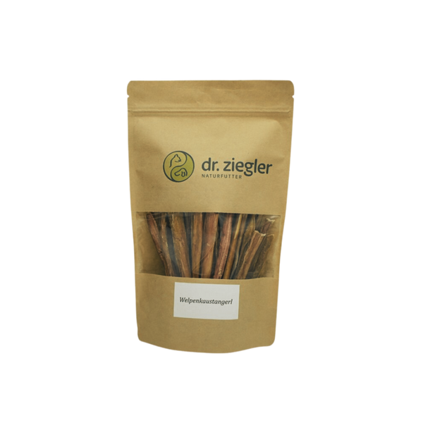 Braune Verpackung mit dem Logo 'dr. ziegler' und der Aufschrift 'Welpenkaustangerl'. Sichtbare Kaustangen im Inneren der Tüte.