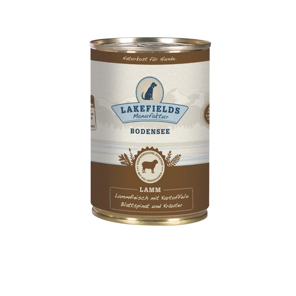 Runde Dose mit dem Etikett 'LAKEFIELDS', Inhalt: Weidelamm mit Blattspinat, Kräutern und Kartoffeln. Die Dose hat einen metallischen Glanz und eine braune Farbfläche.