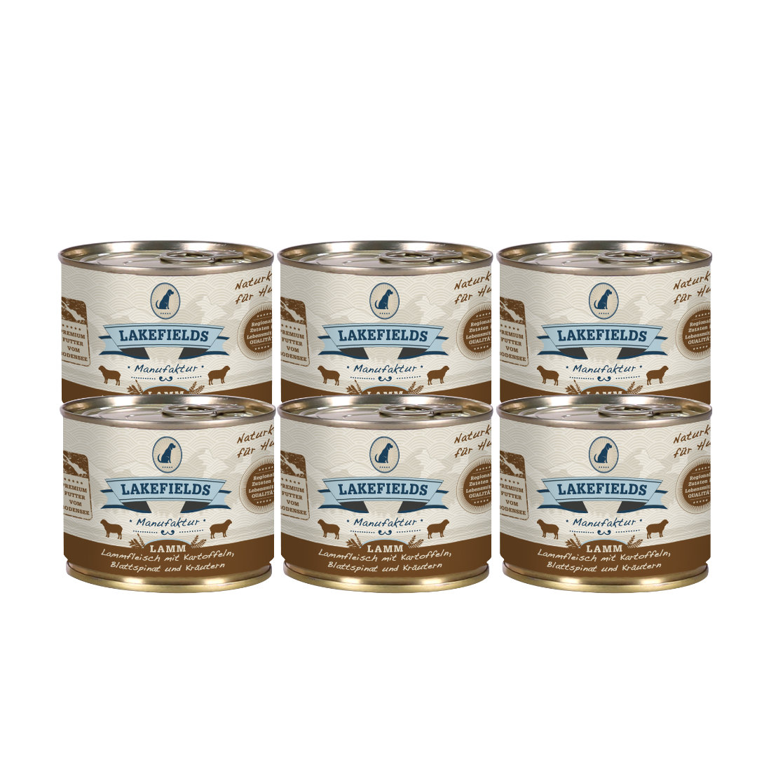 Sechs Runde Dosen mit dem Etikett 'LAKEFIELDS', Inhalt: Weidelamm mit Blattspinat, Kräutern und Kartoffeln. Die Dose hat einen metallischen Glanz und eine braune Farbfläche.