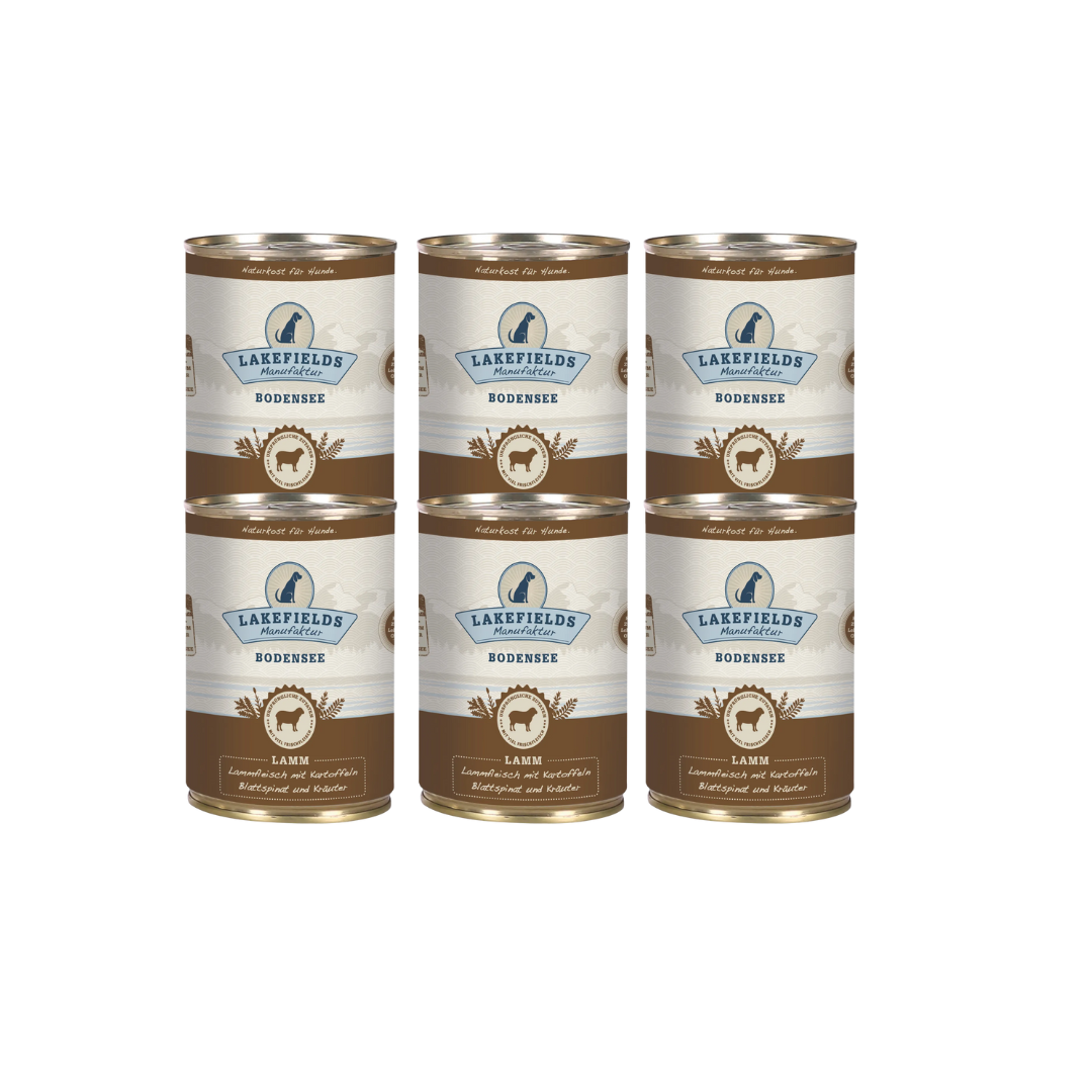 Sechs Runde Dosen mit dem Etikett 'LAKEFIELDS', Inhalt: Weidelamm mit Blattspinat, Kräutern und Kartoffeln. Die Dose hat einen metallischen Glanz und eine braune Farbfläche.