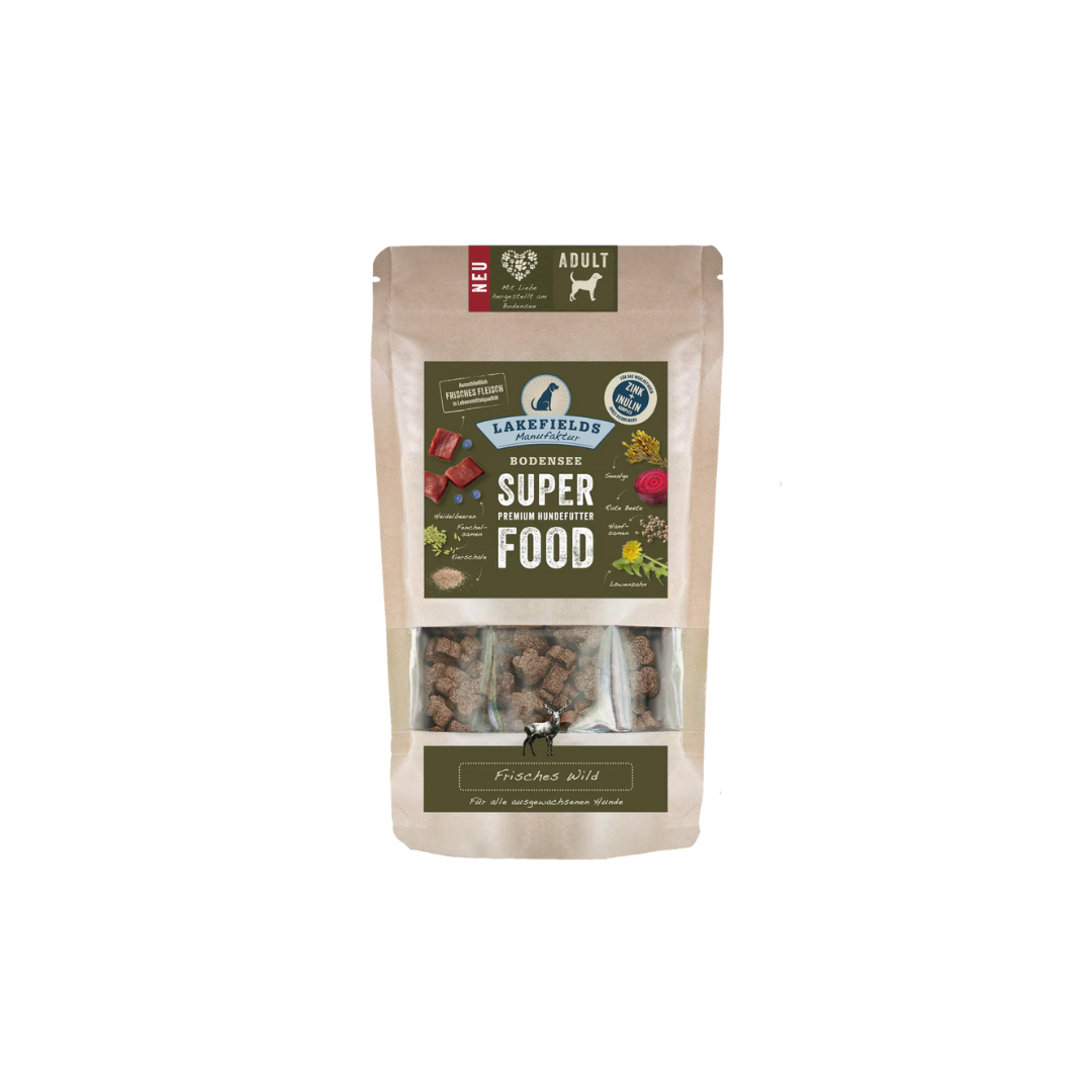 Verpackung von Lakefields Superfood für Hunde, 130g. Grüne Tüte mit Bildern von Wild, Kräutern und dem Text 'ADULT'.