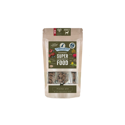 Verpackung von Lakefields Superfood für Hunde, 130g. Grüne Tüte mit Bildern von Wild, Kräutern und dem Text 'ADULT'.
