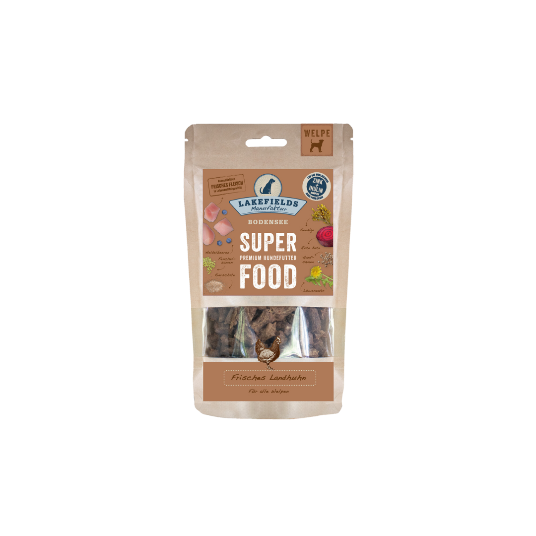 Verpackung von Lakefields Superfood für Hunde, 130g. Braune Tüte mit Bildern von Landhuhn, Kräutern und dem Text 'WELPE'.