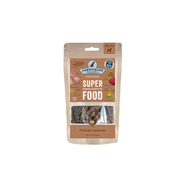 Verpackung von Lakefields Superfood für Hunde, 130g. Braune Tüte mit Bildern von Landhuhn, Kräutern und dem Text 'WELPE'.