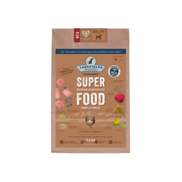 Verpackung von Lakefields Superfood für Hunde, 1 kg. Braune Tüte mit Bildern von Landhuhn, Kräutern und dem Text 'NEU' und 'WELPE'.