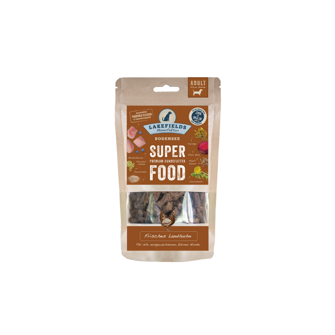 Verpackung von Lakefields Superfood für Hunde, 130g. Braune Tüte mit Bildern von Landhuhn, Kräutern und dem Text 'MINI Adult'.
