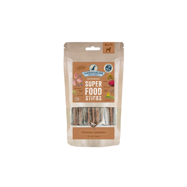 Verpackung von Lakefields Superfood Sticks für Welpen, 130g. Die Tüte zeigt verschiedene Zutaten wie Gemüse und Fleisch, mit einem Hundesymbol.