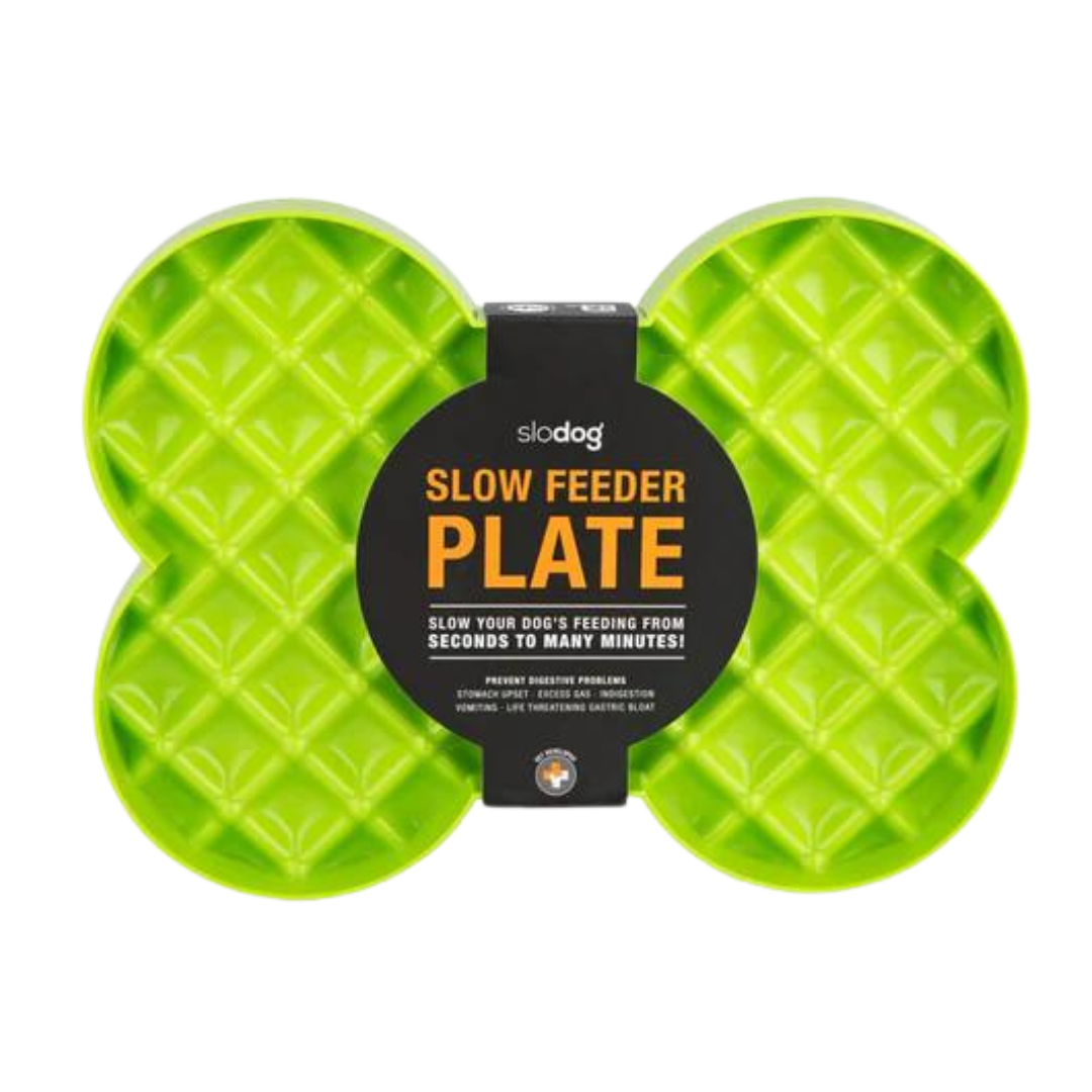 Grüne Futterplatte 'LickiMat Slodog' in Form eines Knochens mit rautenförmigen Vertiefungen. Verpackung zeigt einen Hund und Informationen zur Verwendung.