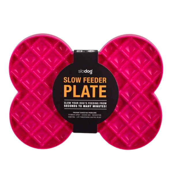 Pinke Futterplatte 'LickiMat Slodog' in Form eines Knochens mit rautenförmigen Vertiefungen. Verpackung zeigt einen Hund und Informationen zur Verwendung.