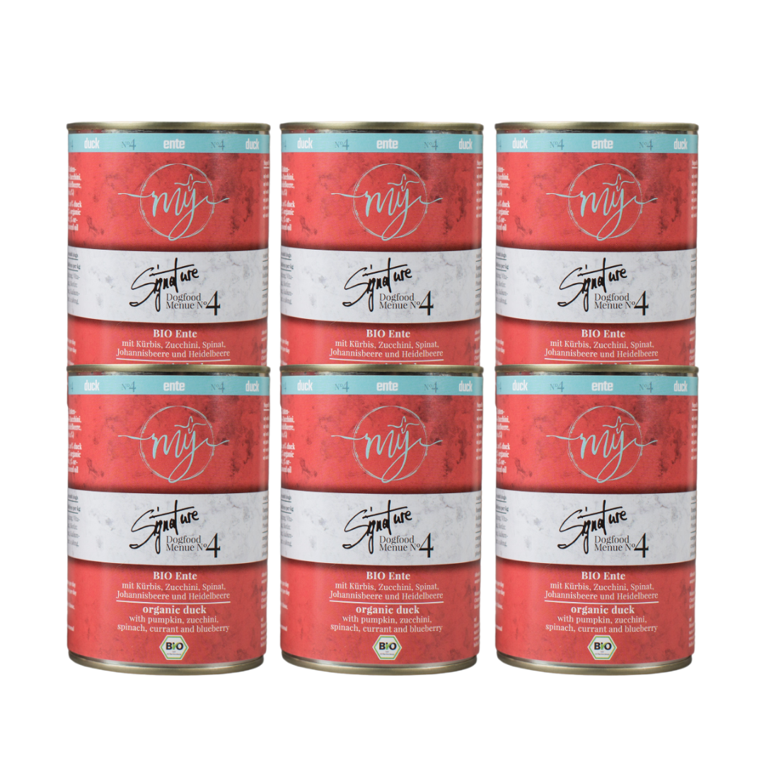 Sechs Dosen für Hundefutter mit rotem Etikett. Aufschrift: my Signature, Dogfood Menue No. 4, BIO Ente und Zutaten wie Kürbis, Zucchini, Spinat, Johannisbeere und Heidelbeere.