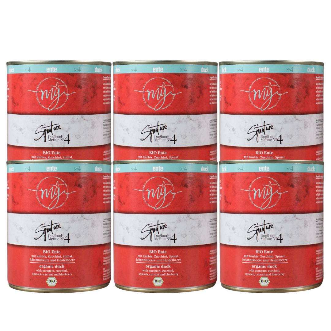 Sechs Dosen für Hundefutter mit rotem Etikett. Aufschrift: my Signature, Dogfood Menue No. 4, BIO Ente und Zutaten wie Kürbis, Zucchini, Spinat, Johannisbeere und Heidelbeere.