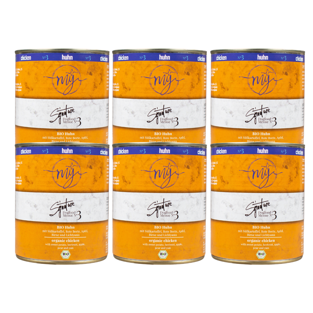 Sechs Dosen Hundefutter mit gelben Etikett. Aufschrift: my Signature, Dogfood Menue No. 3, BIO Huhn und Zutaten wie Süßkartoffel, Rote Beete, Äpfel, Birne.