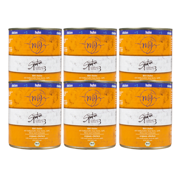 Sechs Dosen Hundefutter mit gelben Etikett. Aufschrift: my Signature, Dogfood Menue No. 3, BIO Huhn und Zutaten wie Süßkartoffel, Rote Beete, Äpfel, Birne.