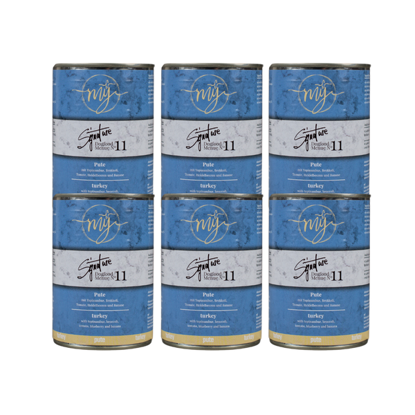 Sechs Dosen Hundefutter mit blauem Etikett. Aufschrift: my Signature, Dogfood Menue No. 11, BIO Pute und Zutaten wie Topinambur, Brokkoli, Heidelbeeren, Tomaten, Bananen,