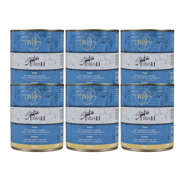 Sechs Dosen Hundefutter mit blauem Etikett. Aufschrift: my Signature, Dogfood Menue No. 11, BIO Pute und Zutaten wie Topinambur, Brokkoli, Heidelbeeren, Tomaten, Bananen,