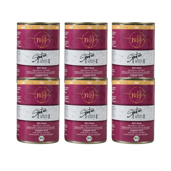 Sechs Dosen Hundefutter mit pinkem Etikett. Aufschrift: my Signature, Dogfood Menue No. 1, BIO Rins und Zutaten wie Quinoa, Zucchini, Süßkartoffeln, Johannsibeeren, Apfel