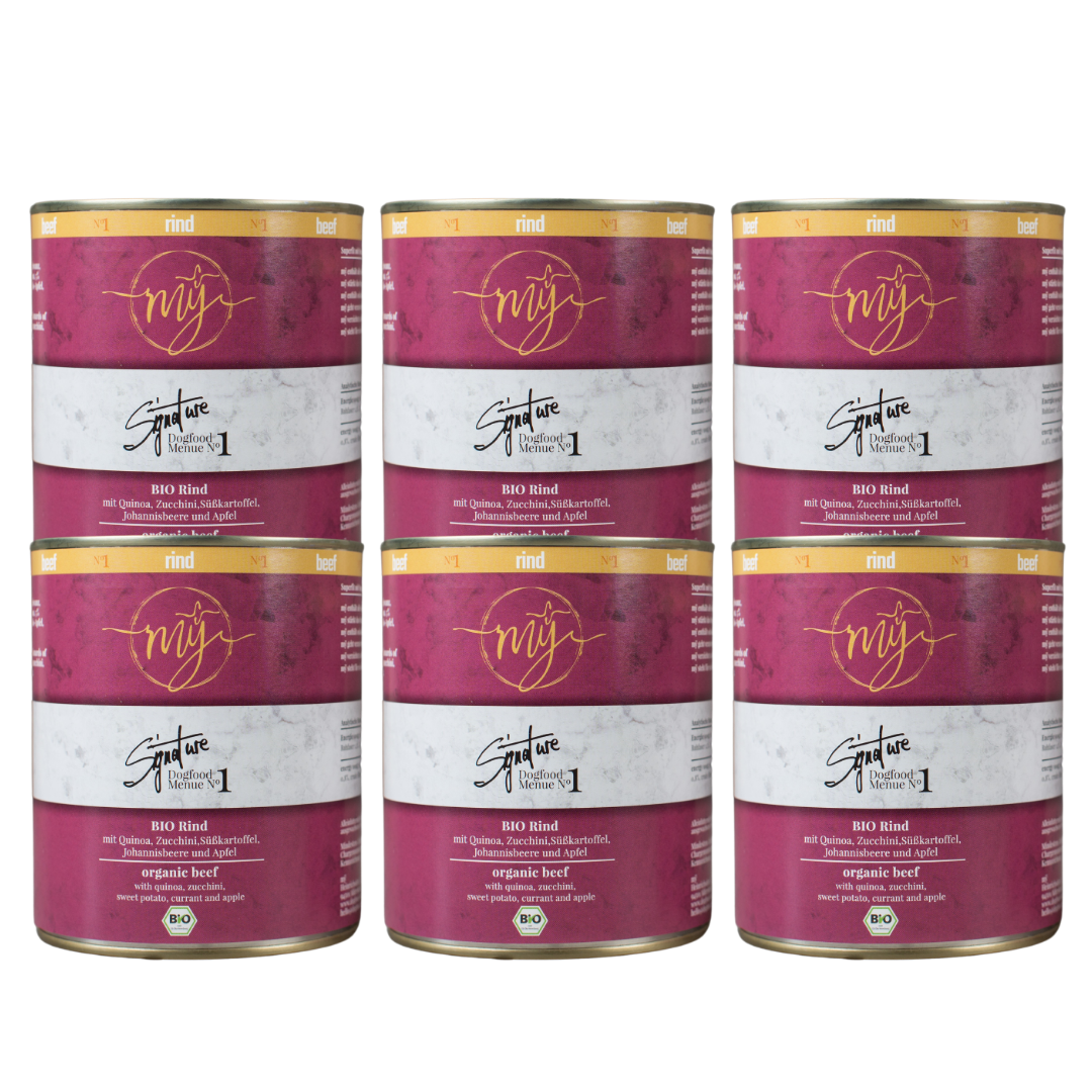 Sechs Dosen Hundefutter mit pinkem Etikett. Aufschrift: my Signature, Dogfood Menue No. 1, BIO Rins und Zutaten wie Quinoa, Zucchini, Süßkartoffeln, Johannsibeeren, Apfel