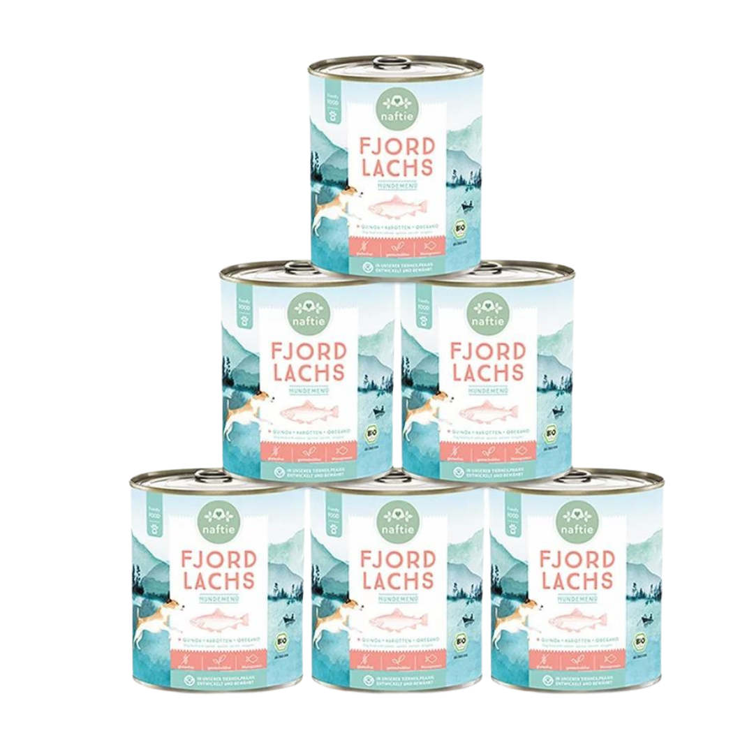 Sechs Runddosen mit dem Produktnamen 'FJORD LACHS' von naftie. Enthält Quinoa, Karotten und Oregano. Abgebildet sind ein Hund und eine Landschaft mit Bergen und Wasser.