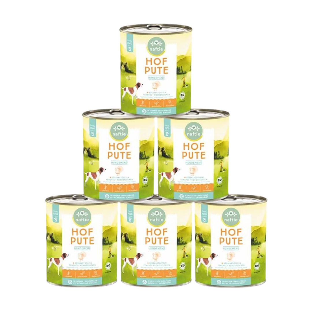 Sechs Dose mit Bio-Hundefutter von naftie, 800g, mit Abbildung eines Hundes und Landschaft im Hintergrund. Aufschrift: 'HOF PUTE HUNDEMENÜ.