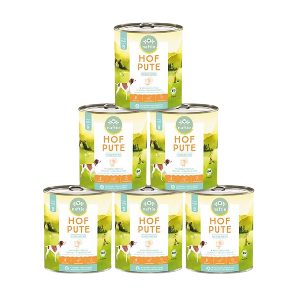 Sechs Dose mit Bio-Hundefutter von naftie, 800g, mit Abbildung eines Hundes und Landschaft im Hintergrund. Aufschrift: 'HOF PUTE HUNDEMENÜ.