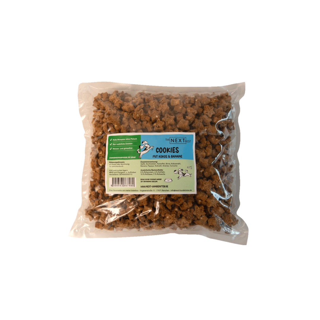 Transparente Verpackung mit 500 g Cookies von der Marke 'NEXT'. Die Cookies haben eine unregelmäßige Form und sind braun. Auf der Vorderseite befindet sich ein Etikett mit Produktinformationen.