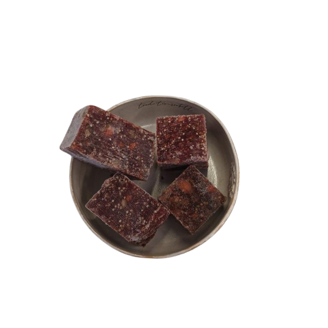 Vier fast quadratische Stücke gemischtes Lammwürfel auf einem grauen, rundem Teller.